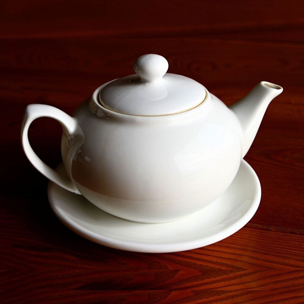Um bule de chá branco de cerâmica em cima de uma mesa.